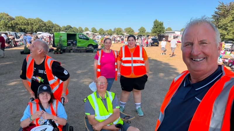 Group of helpers in high vis vests smiling at the camera with the car boot sale in the background